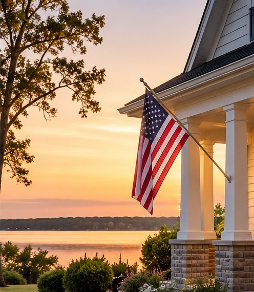 Home with American flag near the water at sunset